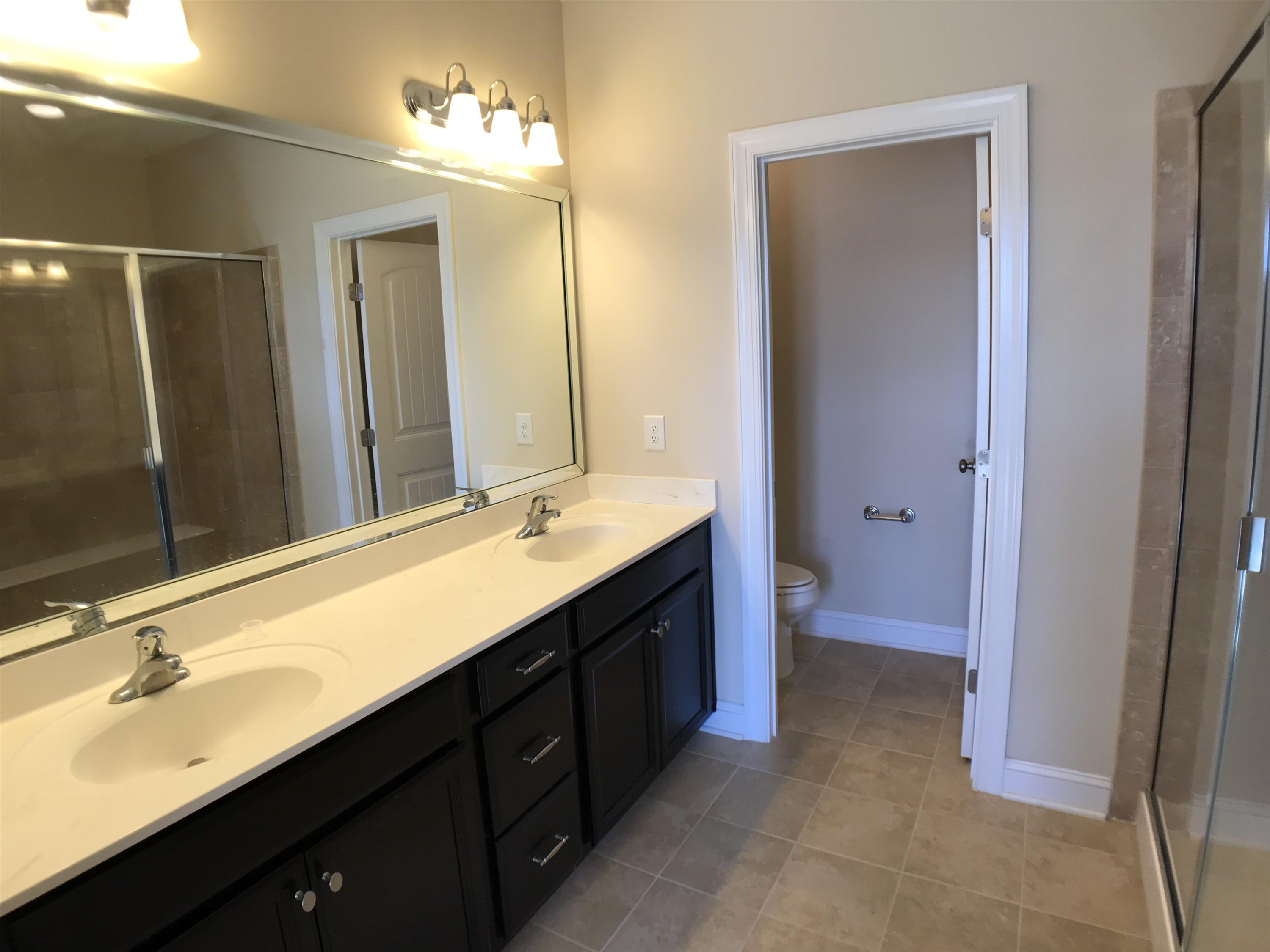 925 Rosepine Drive Cary, NC 27519 - Photo 13 of 21 a bathroom with a double vanity sink a large mirror and a bathtub