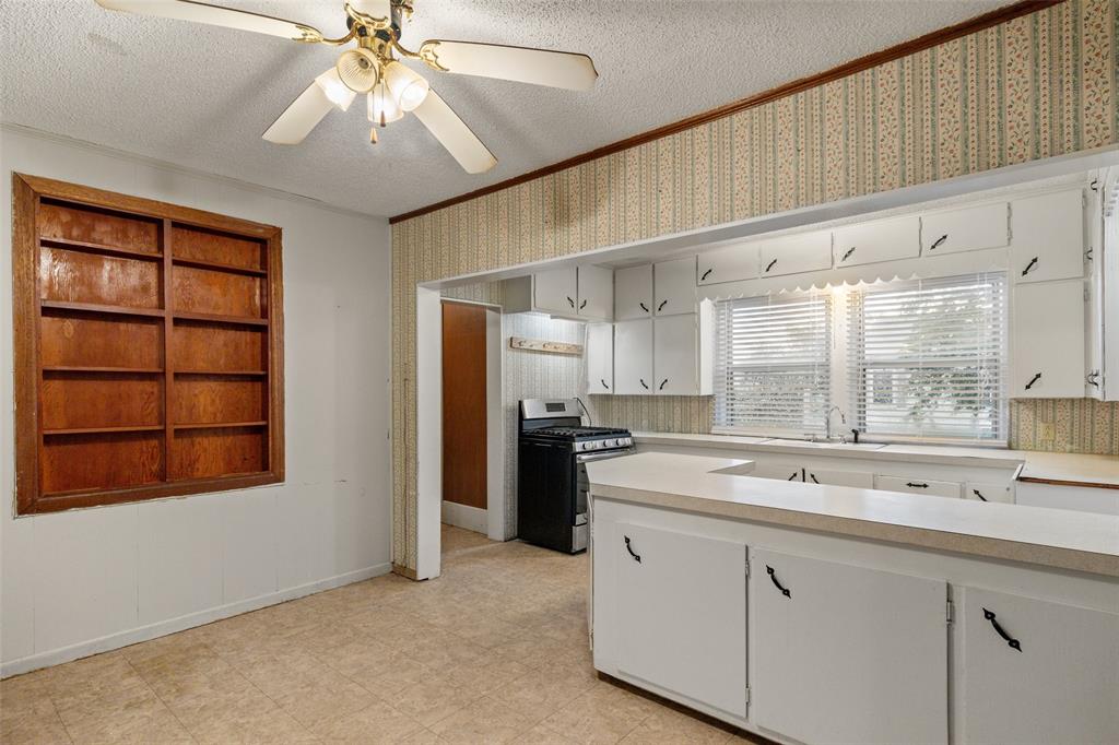 302 West Grogan Street Hamilton, TX 76531 - Photo 11 of 33 Kitchen featuring light countertops, a textured ceiling, ornamental molding, and stainless steel gas stove