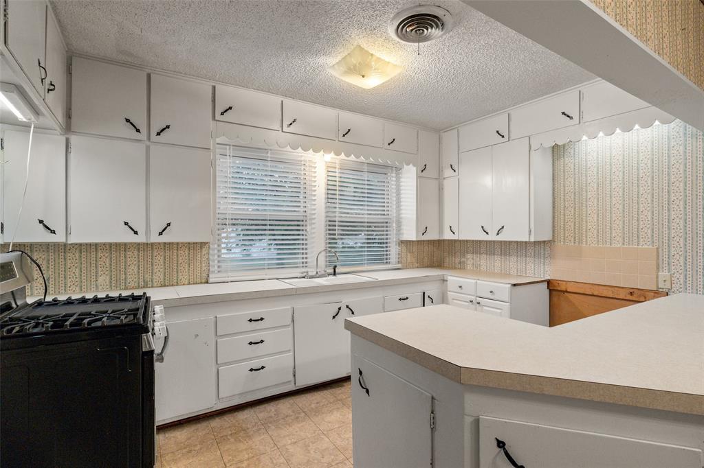 302 West Grogan Street Hamilton, TX 76531 - Photo 13 of 33 Kitchen featuring visible vents, gas range, wallpapered walls, a textured ceiling, and a sink