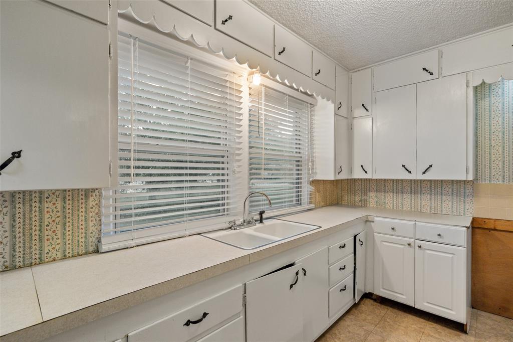 302 West Grogan Street Hamilton, TX 76531 - Photo 15 of 33 Kitchen with a sink, light countertops, white cabinetry, and a healthy amount of sunlight