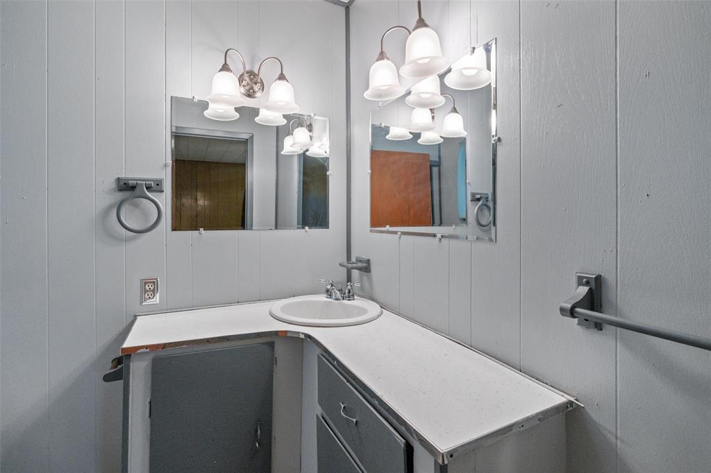 302 West Grogan Street Hamilton, TX 76531 - Photo 23 of 33 Bathroom with an inviting chandelier, a decorative wall, and vanity