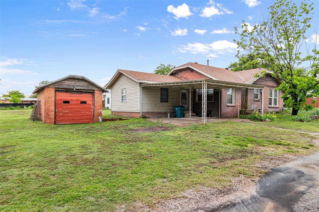 302 West Grogan Street Hamilton, TX 76531 - Photo 3 of 33 Back of property with a garage, an outdoor structure, and a lawn