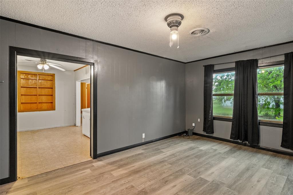 302 West Grogan Street Hamilton, TX 76531 - Photo 6 of 33 Empty room featuring ceiling fan, a textured ceiling, visible vents, light wood-type flooring, and baseboards
