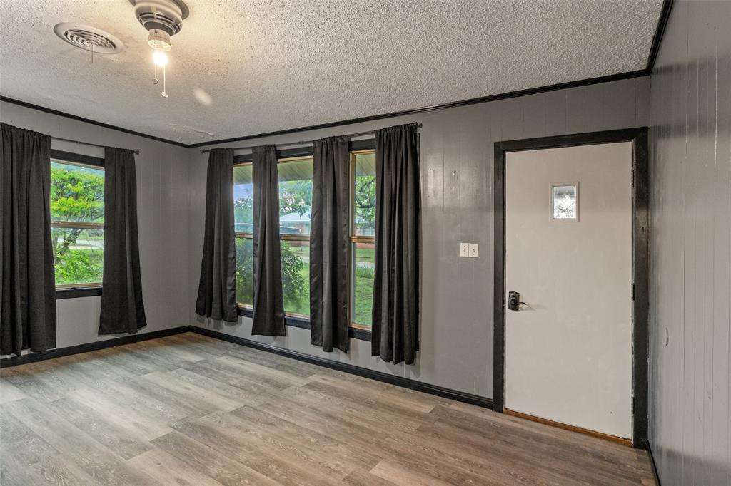 302 West Grogan Street Hamilton, TX 76531 - Photo 7 of 33 Entryway featuring a textured ceiling, visible vents, ornamental molding, and light wood-type flooring