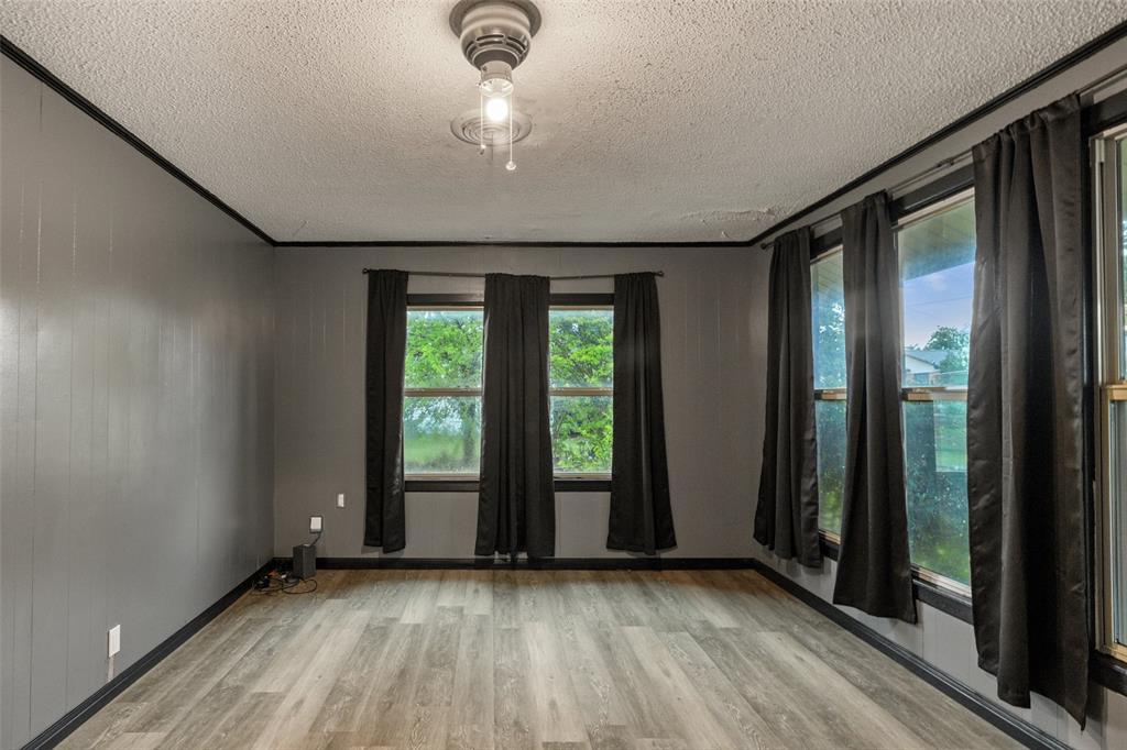 302 West Grogan Street Hamilton, TX 76531 - Photo 8 of 33 Empty room with a textured ceiling, baseboards, and light wood-style floors