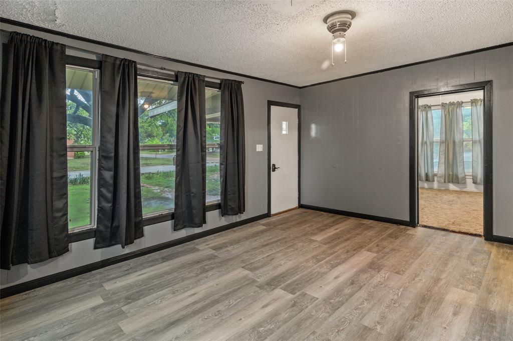 302 West Grogan Street Hamilton, TX 76531 - Photo 9 of 33 Spare room featuring crown molding, a textured ceiling, a healthy amount of sunlight, and wood finished floors