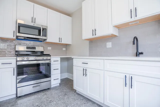 a kitchen with white cabinets and stainless steel appliances