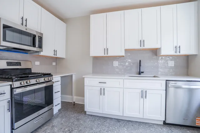 a kitchen with stainless steel appliances granite countertop grey cabinets a stove a sink and dishwasher