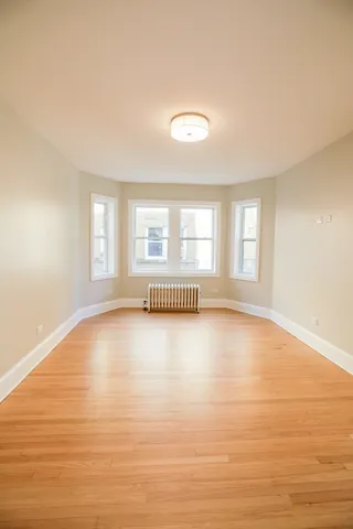 a view of an empty room with a window and wooden floor