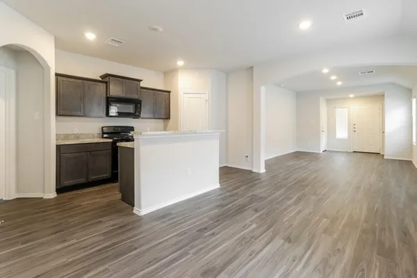 a view of kitchen with stainless steel appliances granite countertop a stove top oven a sink and a refrigerator