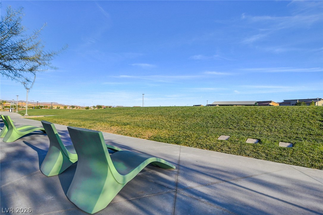 7330 North Decatur Boulevard, Unit 6 North Las Vegas, NV 89084 - Photo 34 of 42 Green benches line a paved path, offering tranquil seating by a vibrant grassy hill.