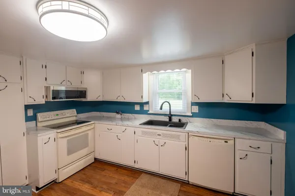 a kitchen with granite countertop white cabinets white appliances and sink