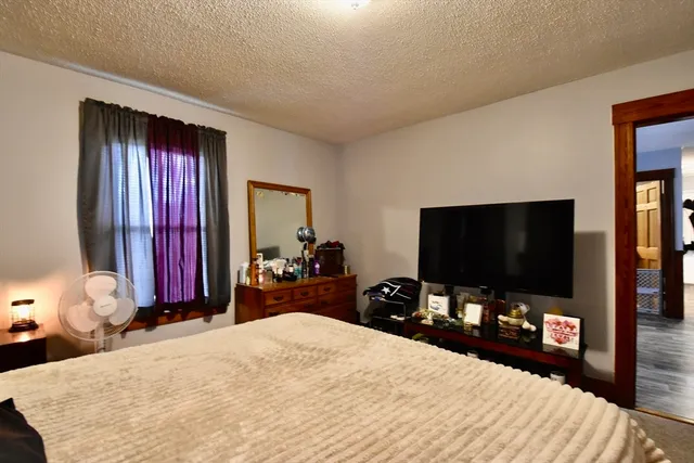 a bedroom with a bed and a flat tv screen on dresser