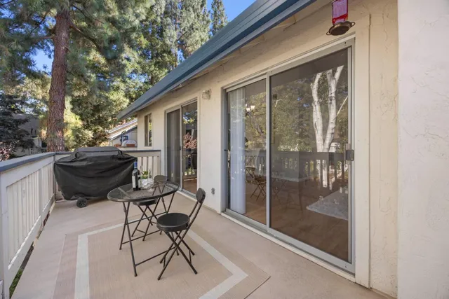 a balcony with table and chairs and potted plants