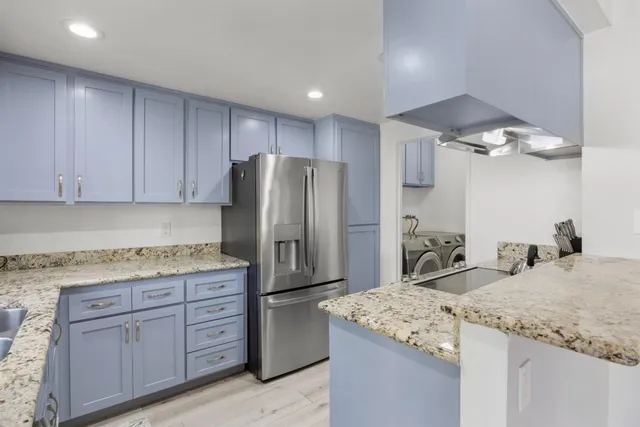 a kitchen with stainless steel appliances granite countertop a sink refrigerator and cabinets