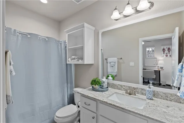 a bathroom with a granite countertop sink vanity mirror and toilet