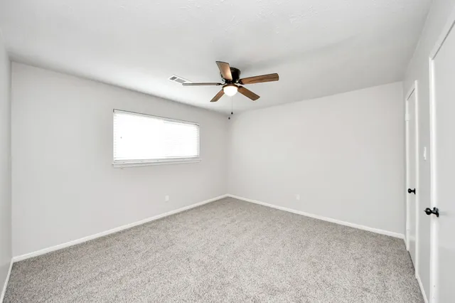 an empty room with a window and a ceiling fan