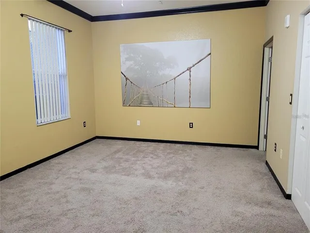 a view of an empty room with painting on the wall and a window