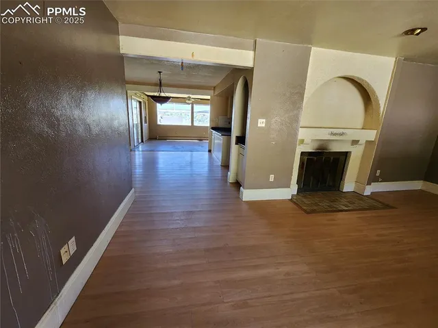 a view of a livingroom with wooden floor a fireplace and entryway