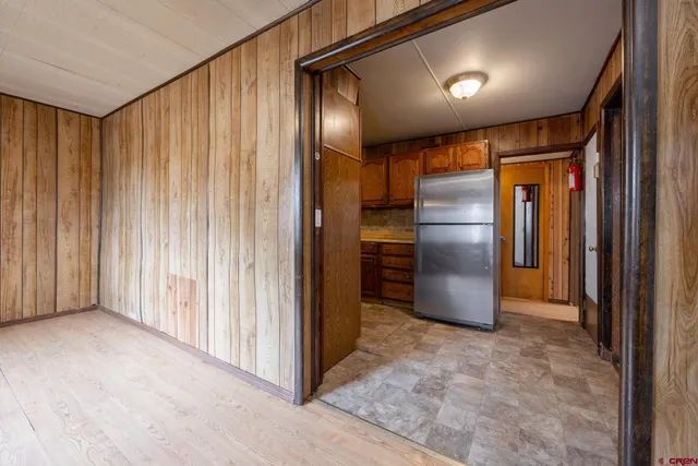 a view of a hallway with stainless steel appliances granite countertop lots of cabinets and wooden floor
