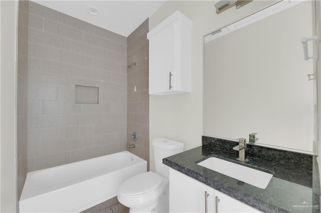 409 Rafael Drive San Juan, TX 78589 - Photo 13 of 20 a bathroom with a granite countertop sink a toilet a mirror and bathtub