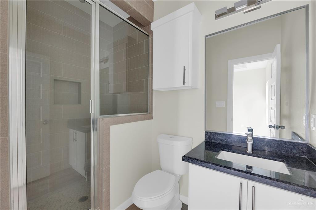 409 Rafael Drive San Juan, TX 78589 - Photo 18 of 20 a bathroom with a granite countertop sink a toilet and shower