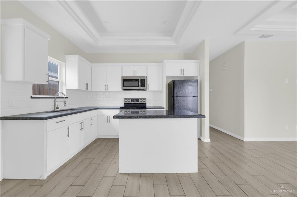409 Rafael Drive San Juan, TX 78589 - Photo 10 of 20 a kitchen with granite countertop a refrigerator a sink dishwasher and white cabinets with wooden floor