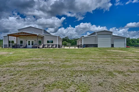 a view of a house with a big yard and large trees
