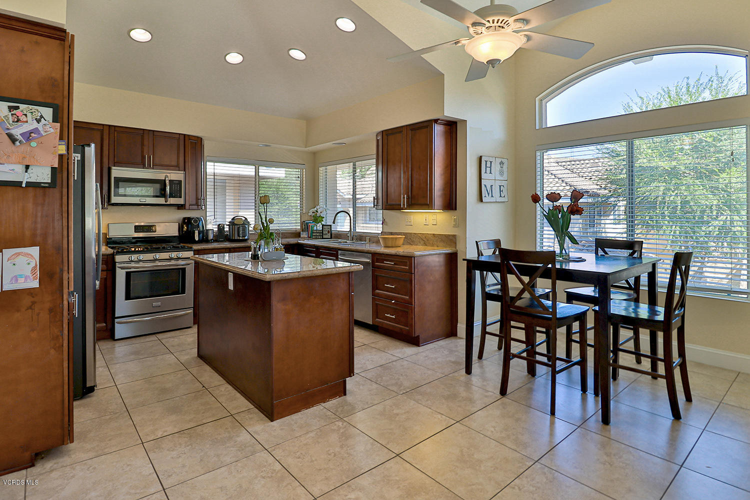 a kitchen with stainless steel appliances granite countertop wooden cabinets a dining table and chairs