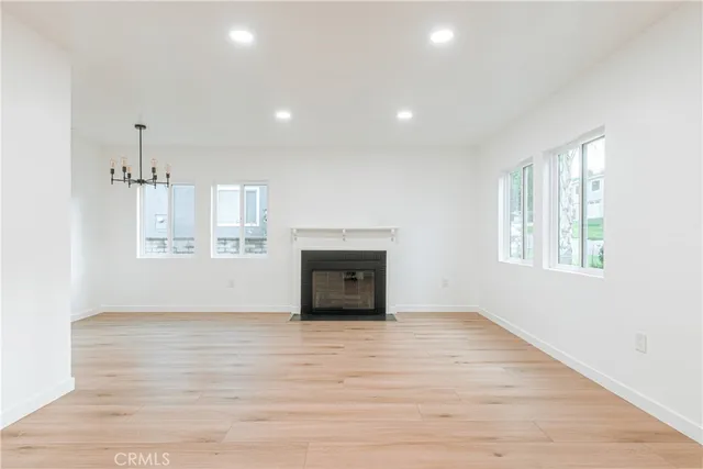 an empty room with wooden floor fireplace and windows
