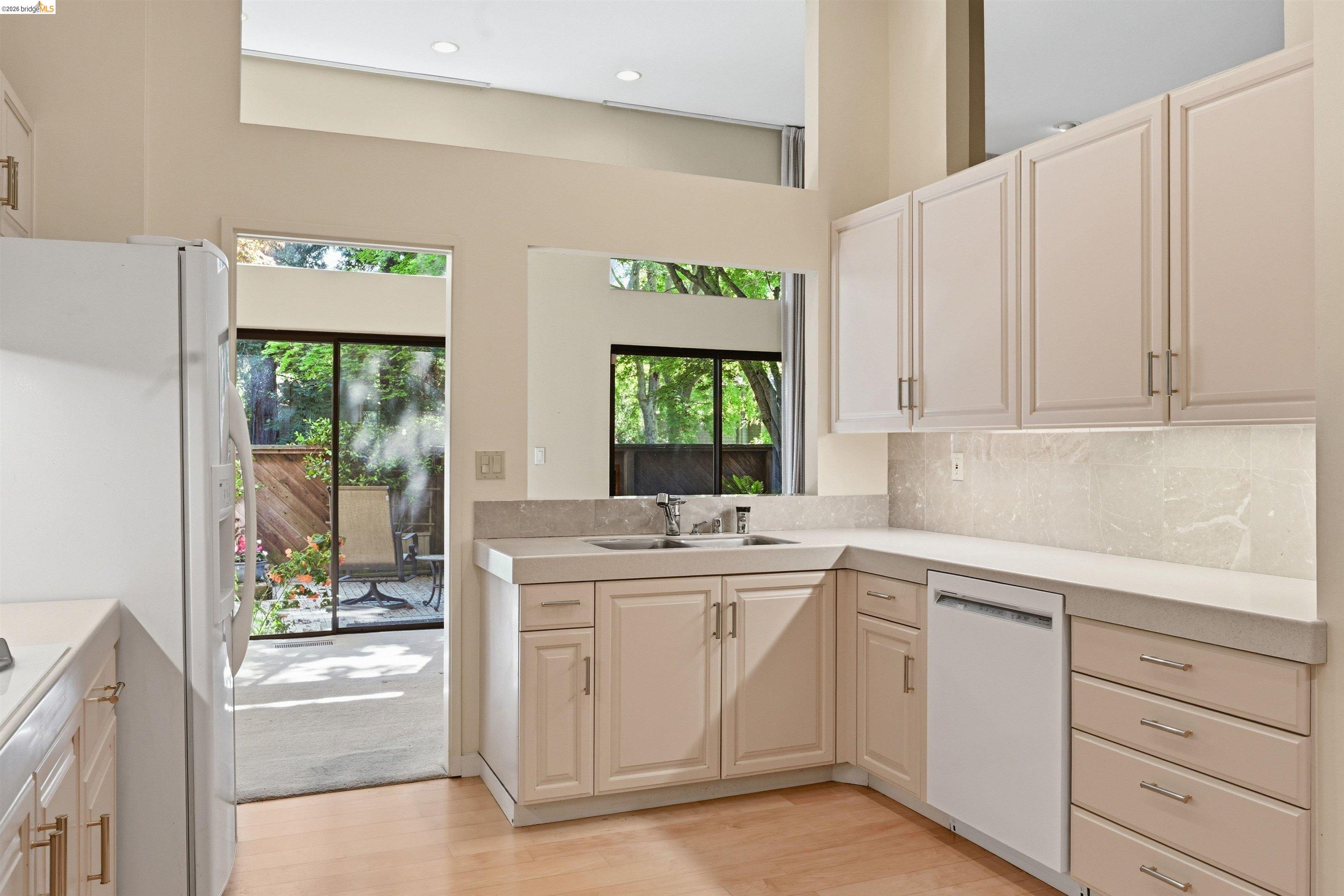 1925 Piper Ridge Court Walnut Creek, CA 94597 - Photo 3 of 27 Kitchen featuring white appliances, light countertops, light wood finished floors, backsplash, and a high ceiling