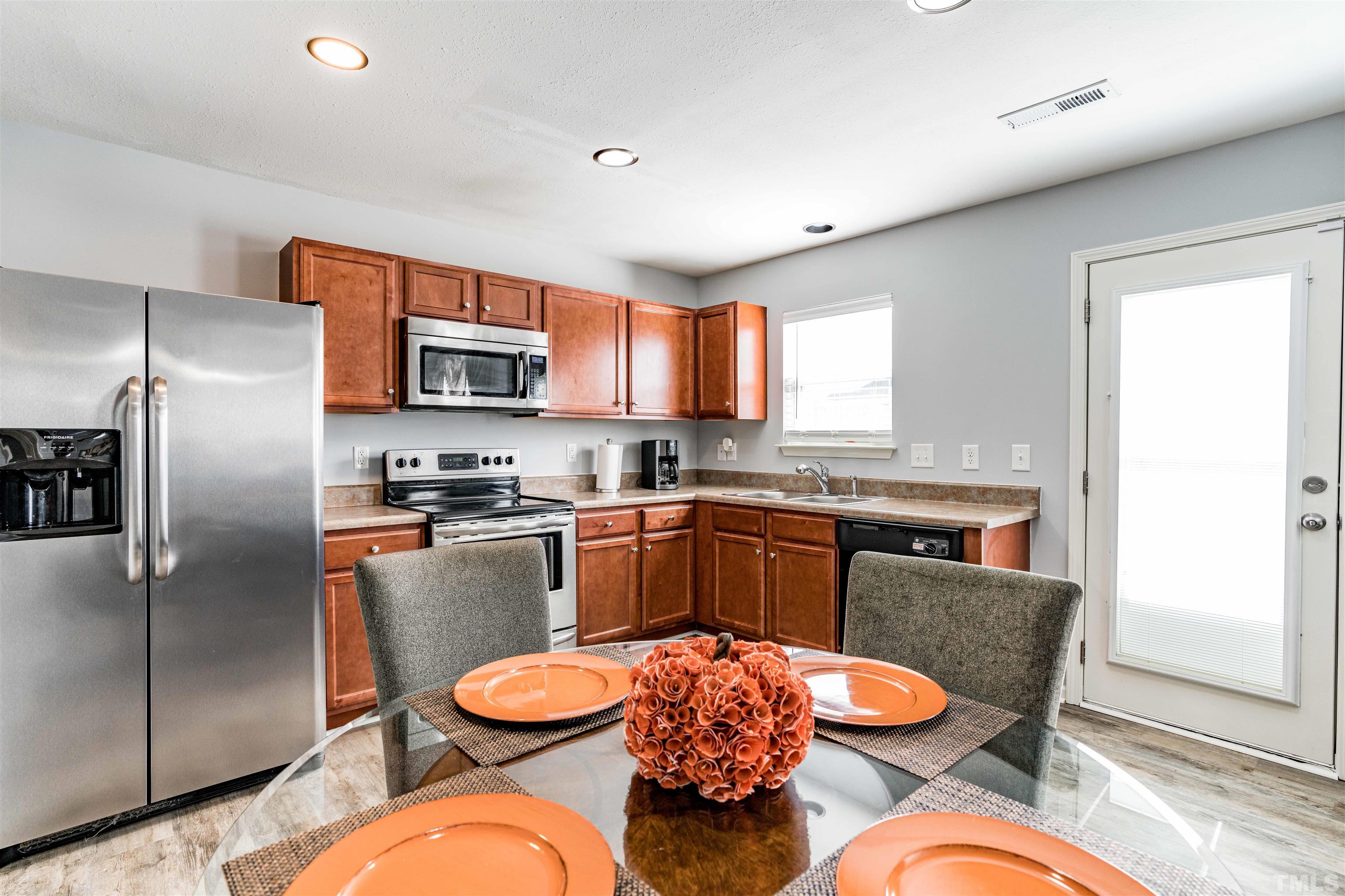3902 Evans Drive Raleigh, NC 27610 - Photo 13 of 31 a kitchen with stainless steel appliances a dining table chairs and wooden floor