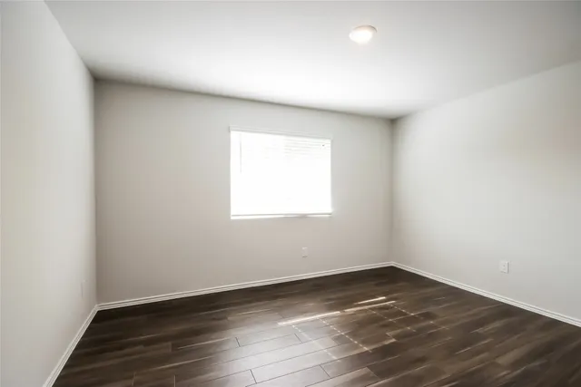 an empty room with wooden floor and window