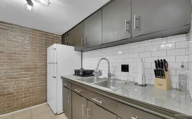 a kitchen with stainless steel appliances a sink a refrigerator and cabinets
