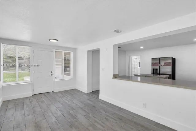 a view of a big room with wooden floor and windows