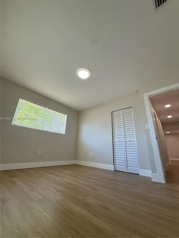 a view of an empty room with wooden floor and closet