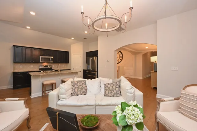 a living room with stainless steel appliances furniture a rug and a kitchen view