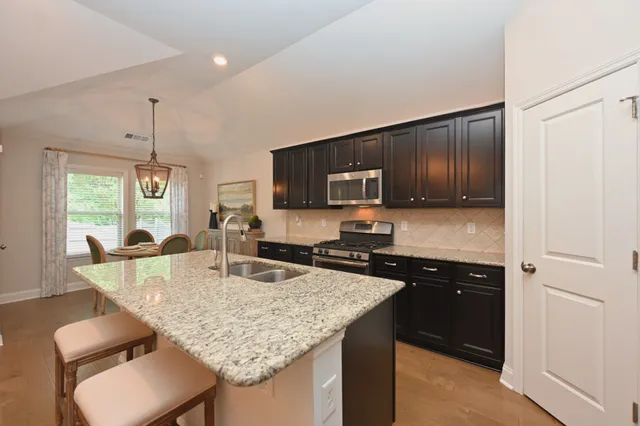 a kitchen with kitchen island granite countertop a sink stainless steel appliances and windows