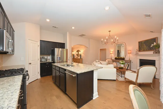 a kitchen with stainless steel appliances granite countertop a stove oven a refrigerator a kitchen island with couches chairs and fireplace