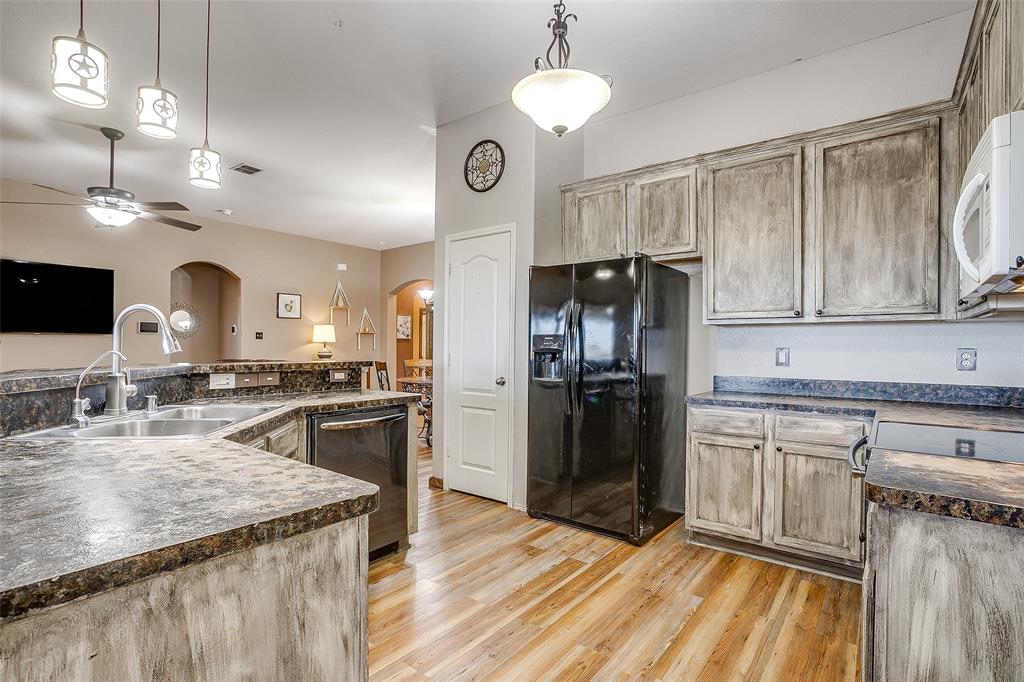 10905 Soft Shell Drive Venus, TX 76084 - Photo 11 of 21 a kitchen with granite countertop kitchen island stainless steel appliances a sink cabinets a refrigerator and a stove
