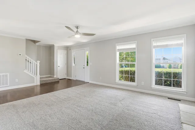 a view of an empty room with a window and kitchen view