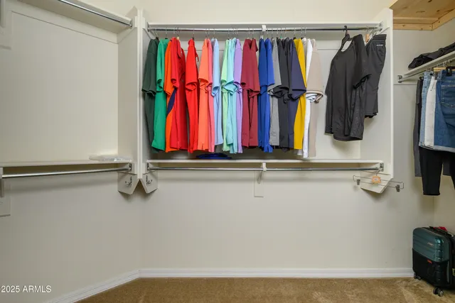 a view of walk in closet with clothes and shoes