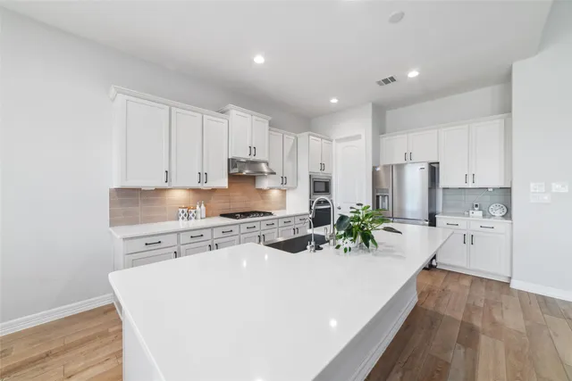 a kitchen with refrigerator a stove and white cabinets