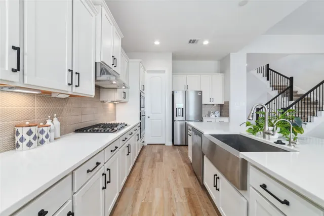 a kitchen with stainless steel appliances granite countertop a sink a stove and a refrigerator
