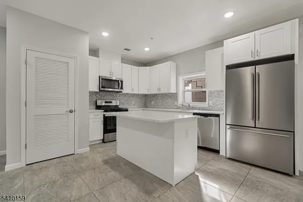 a kitchen with stainless steel appliances granite countertop a refrigerator and a stove top oven