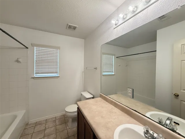 a bathroom with a granite countertop sink a mirror and a toilet