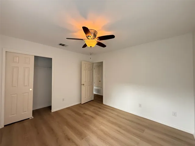 an empty room with wooden floor and a ceiling fan
