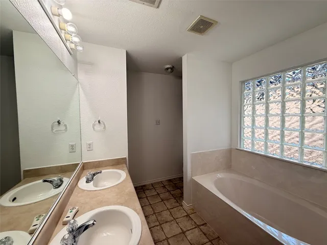 a bathroom with a tub sink and mirror