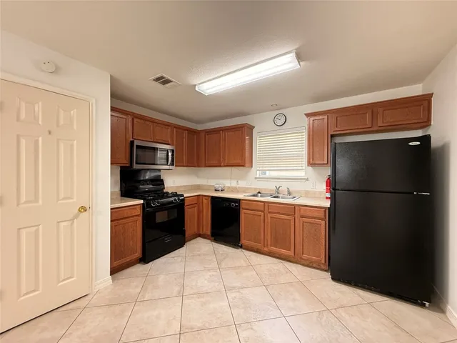 a large kitchen with a refrigerator a stove top oven a sink and dishwasher
