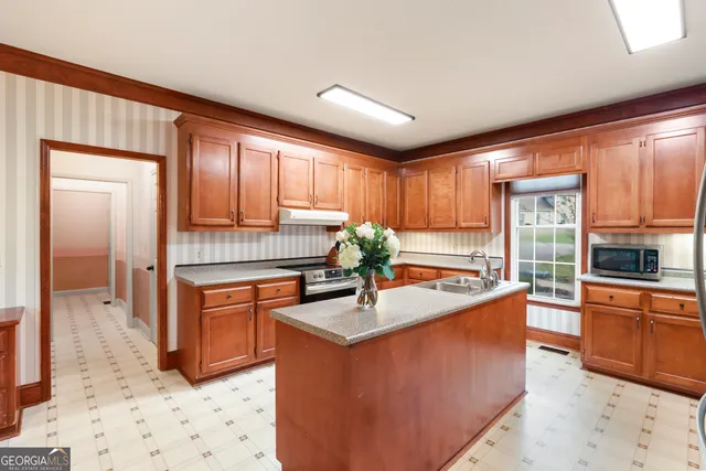 a kitchen with stainless steel appliances granite countertop a sink stove refrigerator and cabinets